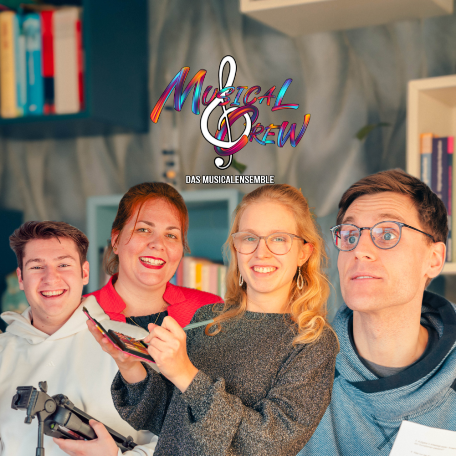 Vier Personen lächeln in einem stilvollen Raum, umgeben von Büchern und Musiknoten.